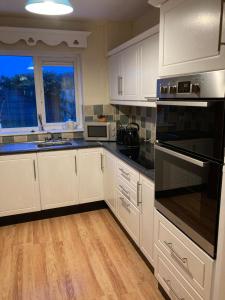 una cocina con armarios blancos y electrodomésticos negros en Ember, en Ballygerry