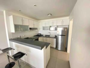 uma cozinha com armários brancos e um frigorífico de aço inoxidável em VISTAMAR PARACAS Depa de playa la mejor vista em Paracas