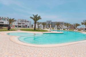 - une piscine dans un complexe avec des palmiers et des bâtiments dans l'établissement VISTAMAR PARACAS Depa de playa la mejor vista, à Paracas