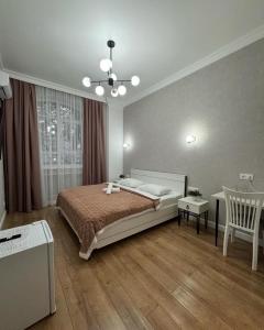 a bedroom with a bed and a table and a chair at Rose Art hotel in Astana