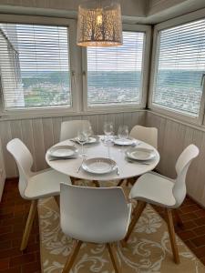 een eettafel met witte stoelen en een kroonluchter bij Premium Apartment 70qm 2,5 Zimmer Küche, Smart TV, Garage, WiFi in Heidenheim an der Brenz