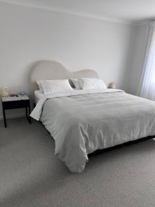 sypialnia z dużym łóżkiem z białą pościelą i poduszkami w obiekcie All the comforts at the beach w mieście Waitarere