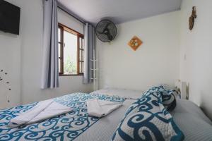 a bedroom with a bed with a blue and white comforter at Hostel Cabo Frio in Cabo Frio