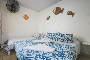 a bedroom with a bed with blue and white sheets at Hostel Cabo Frio in Cabo Frio