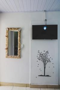 a wall with a tree and a mirror at Hostel Cabo Frio in Cabo Frio