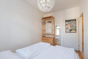 ein weißes Schlafzimmer mit einem Bett und einem Kronleuchter in der Unterkunft Zentral und ruhig bei Schönbrunn in Wien