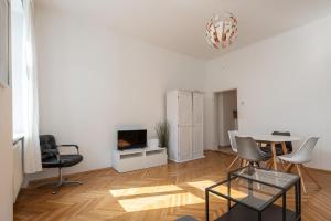 ein Wohnzimmer mit einem Tisch, Stühlen und einem TV in der Unterkunft Zentral und ruhig bei Schönbrunn in Wien