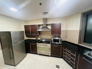 AlRaef Luxury Apartments في دبي: مطبخ مع أجهزة ستانلس ستيل ودواليب بنية