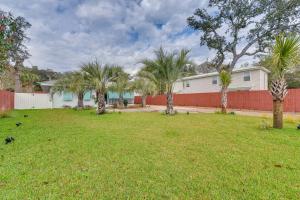 a yard with palm trees and a fence at Emerald Coast Getaway Near Boardwalk and Breweries! in Fort Walton Beach