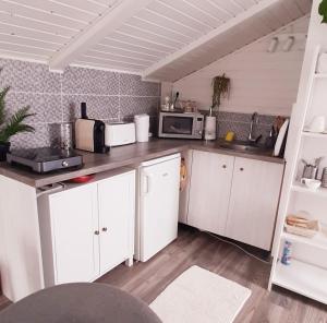 a kitchen with white cabinets and a microwave at Holdfény Apartman in Balatongyörök