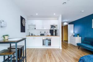 a kitchen and living room with a table and a couch at Stylish Media City Apartment, Sleeps 3, Darts Board, Smart TV, Tram Stop, Long Term Disc in Manchester