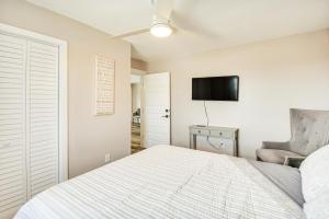 a bedroom with a bed and a chair and a television at Bright Kitty Hawk Home with Hot Tub, Walk to Beach! in Kitty Hawk