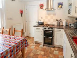 a kitchen with a stove and a table with a table cloth at Pelham House in Keswick