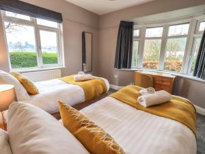 a hotel room with three beds and windows at Curlew Cottage at Hawkshead in Ambleside