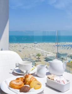 un tavolo con un piatto di dolci e tazze e una spiaggia di Grand Meeting Hotel a Rimini