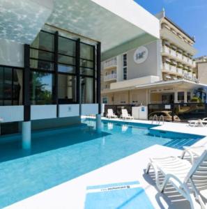 una grande piscina con sedie e un edificio di Grand Meeting Hotel a Rimini