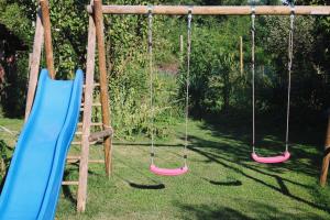 a swing set with four swings in a yard at Apartment Hiža 38 in Mala Subotica