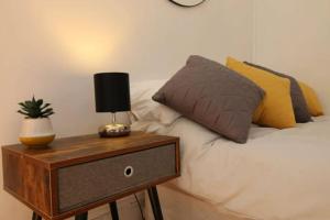 a bed with pillows and a nightstand with a lamp on it at Big Value Bedsit by Property Promise in Cardiff