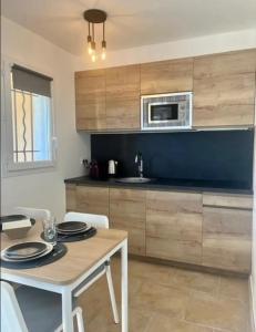 - une cuisine avec une table et un four micro-ondes dans l'établissement DOMAINE LOU BEL AZUR - Charmant, à Saint-Laurent-du-Var