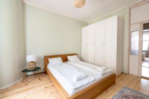 een slaapkamer met een bed met witte lakens en een tafel bij 2ndhomes Bright 125m2 4BR City Center Apartment with the Great Views in Helsinki