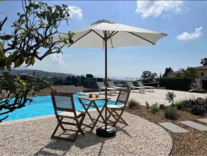 une table et deux chaises sous un parasol à côté d'une piscine dans l'établissement DOMAINE LOU BEL AZUR - Charmant, à Saint-Laurent-du-Var
