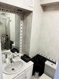 a bathroom with a sink and a toilet and a mirror at Apartamentos Torre de Marbella El Fuerte - Heart of Marbella, Steps from the Beach in Marbella