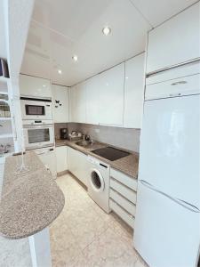 uma cozinha com armários brancos e um frigorífico branco em Apartamentos del Fuerte Marbella - Centro y Playa em Marbella