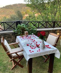 una mesa con un mantel blanco con rosas. en ŞİRİNCE BAHÇE OTEL, en Selçuk