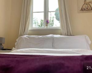 a bed with white sheets and a window in a bedroom at The Wheatsheaf in Bramley