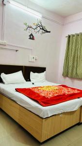 a bedroom with a bed with a red blanket on it at Aashapurti Hotel in Aurangabad