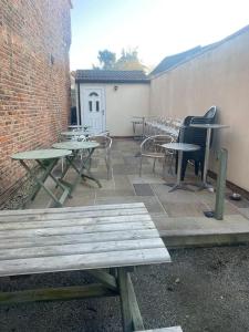 een patio met picknicktafels en stoelen en een bakstenen muur bij 3 x Double Bedroomed Apartment, Snaith in Snaith