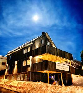 un edificio de madera con la luna en el fondo en 3-roms leilighet, Svolvær, Lofoten, en Svolvær