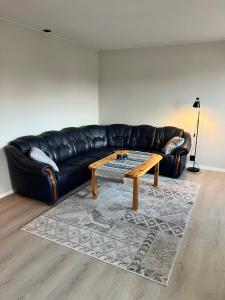 1 sofá de cuero negro con mesa de centro en la sala de estar en 3-roms leilighet, Svolvær, Lofoten, en Svolvær