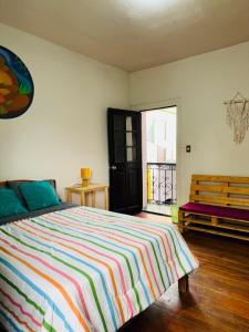 a bedroom with a bed with a colorful striped blanket at Maison Verte - Budget Edition in Arequipa