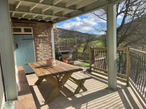 a wooden picnic table on a porch with a grill at Avondale in Llangollen