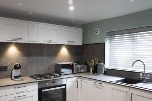 Una cocina con gabinetes blancos, un fregadero y un microondas. en Botanic Mews, en Southport