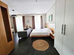 ティラナにあるMagnet Residence Condo 2 self check inのベッドとソファと椅子のある寝室