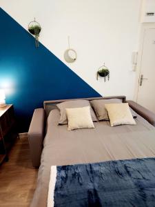 uma cama grande num quarto com uma parede azul em Studio B aux pieds des Thermes em Néris-les-Bains