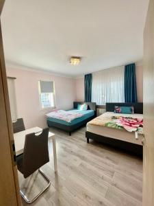 a room with two beds and a table and a chair at Leo Apartment Zentrum Rüsselsheim in Falkenberg