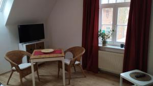 een woonkamer met een tafel en stoelen en een televisie bij Wohnen auf dem Bauernhof in Laatzen