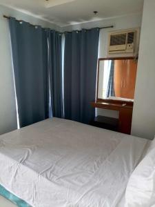 a bedroom with a bed with blue curtains and a window at Birchtower studio in Manila
