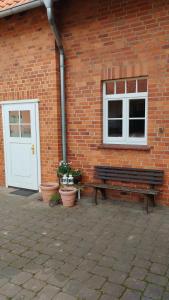 a bench in front of a brick building with a door at Wohnen auf dem Bauernhof in Laatzen