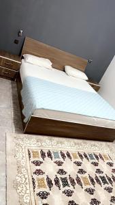 uma cama com uma cabeceira de madeira e um tapete em Atlantis em Nouakchott