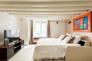 een witte slaapkamer met een bed en een televisie bij Rivoli Vieille du temple in Parijs