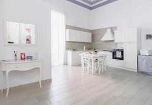 una cucina con armadi bianchi, tavolo e sedie di Gli Appartamenti della Villa a Santa Maria Capua Vetere