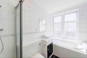 y baño blanco con lavabo y ducha. en Luxury 3 bedroom, 3 bath apt by Oxford St & Soho, en Londres