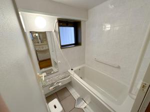 Baño blanco con bañera y lavamanos en Fukuoka - Apartment - Vacation STAY 00143v en Fukuoka
