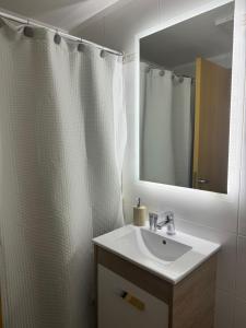 Baño blanco con lavabo y espejo en DEPARTAMENTO Céntrico MENDOZA en Mendoza