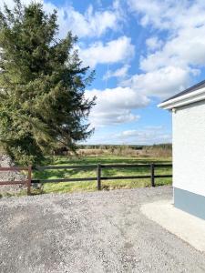 a fence and a tree in a field at Pine View In The Heart Of The West in Lisacul