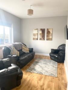 a living room with a black leather couch and a rug at Pine View In The Heart Of The West in Lisacul